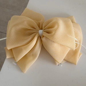 Detailed macro view of yellow gingham bow hair clip with white ribbon and crystal beads