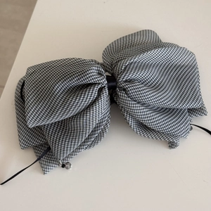 Close-up of black and white gingham bow hair claw clip with crystal pendant details