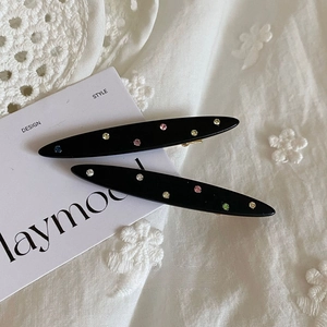 Detail view of black resin hair clips with colorful rhinestones on white lace background
