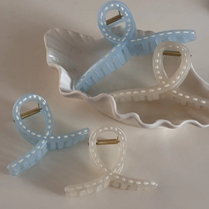 Detail of light blue and cream dotted hair claws in a decorative white ceramic dish