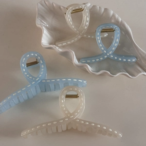 Minimalist blue and cream hair claw clips set with dotted patterns on a shell tray
