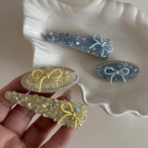 Dettaglio di fermagli per capelli con cristalli blu e gialli su un vassoio di ceramica