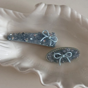 Dettaglio di fermagli per capelli in cristallo azzurro con elegante fiocco su vassoio