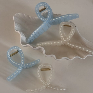 Macro shot of blue and cream resin hair claws with white polka dots and gold springs