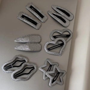 Détail de barrettes argentées scintillantes en forme de cœur et d'étoile avec paillettes
