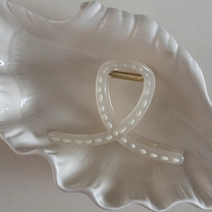 Close-up of white polka dot hair claw clip with gold spring in a shell tray