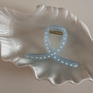Detail view of light blue hair claw with white polka dots on a shell-shaped tray