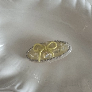 Dettaglio macro di un fermaglio per capelli ovale giallo chiaro con fiocco e strass