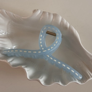 Detail of light blue resin hair claw with white polka dots in a white ceramic dish