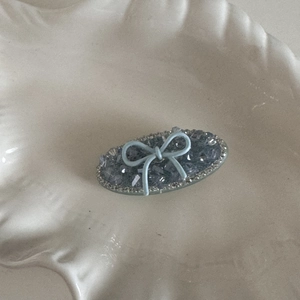 Dettaglio del fermaglio per capelli in cristallo blu con fiocco su vassoio a conchiglia
