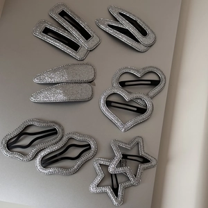 Détail de 12 barrettes à cheveux argentées pailletées en forme d'étoile et cœur
