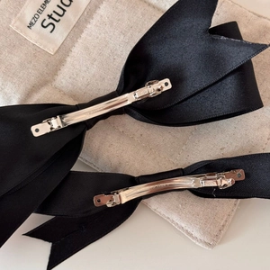 Close-up of black satin bow hair clips with silver spring clip and metal detail