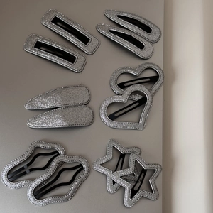 Détail de pinces à cheveux pailletées argentées en formes de cœur, d'étoile et géométriques