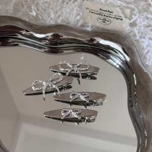 Set of 4 silver bow hair clips with rhinestones on a mirror tray for women