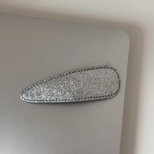 Détail d'une pince à cheveux goutte d'eau à paillettes argentées et coutures noires