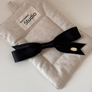 Detailed shot of a black satin bow hair clip with an oval gold metal buckle accent