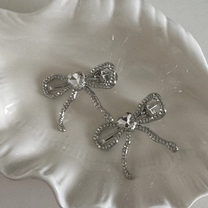 Détail macro d'une pince à cheveux nœud argenté avec strass cœur et pampille