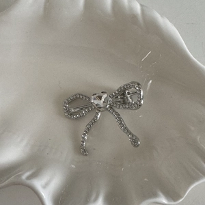 Détail d'une pince à cheveux nœud argenté avec strass brillants et cristal de cœur