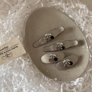Detailed macro shot of four rhinestone cherry hair clips in a ceramic tray