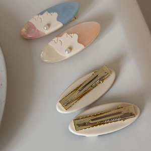 Detailed close-up of oval hair clip with artistic profile and white pearl accent