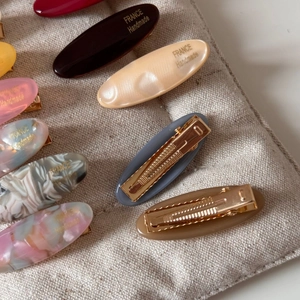 Close-up of macaron acetate oval hair clips with golden letters and metal duckbill clips