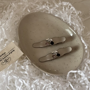 Detailed close-up of alloy cherry hair clips with rhinestones on a ceramic tray
