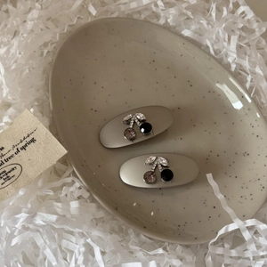 Detail view of rhinestone cherry hair clips on a ceramic tray with decorative shred