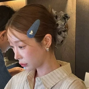 Barrette ovale en jean bleu avec décoration de cœur argenté portée sur les cheveux