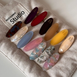 Close-up of assorted oval acetate hair clips in macaron colors with metal clasp details