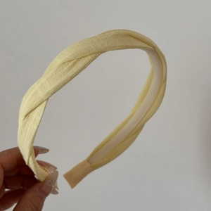 Détail du serre-tête tressé jaune pâle avec tissu texturé sur monture flexible