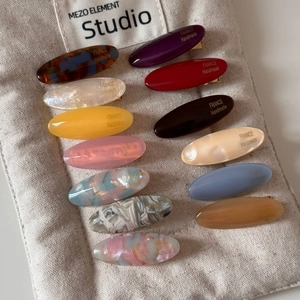 Close-up of 12 colorful oval acetate hair clips in macaron colors and marble textures