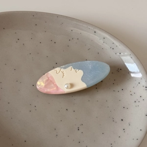 Close-up of artistic face silhouette hair clip with blue pink acetate and pearl detail