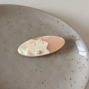 Artistic oval hair clip with pearlescent textures, face profile pattern and pearl detail
