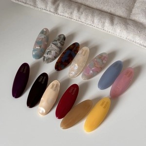 Macro shot of twelve colorful acetate hair clips with gold letters and marble textures