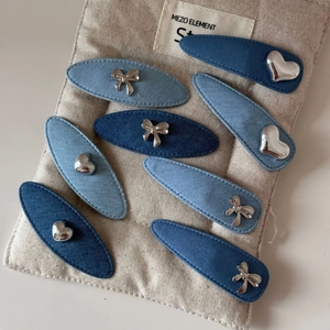 Détail d'un lot de 8 barrettes en denim avec boucles métalliques argentées en cœur et nœud