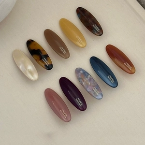 Close-up of assorted macaron color oval acetate hair clips with gold handmade lettering