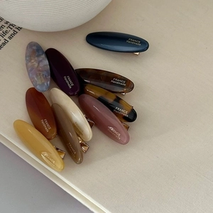 Close-up of colorful acetate oval hair clips featuring elegant gold France handmade logo lettering