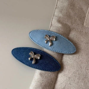 Gros plan de barrettes ovales en denim avec nœuds argentés sur un sac en toile