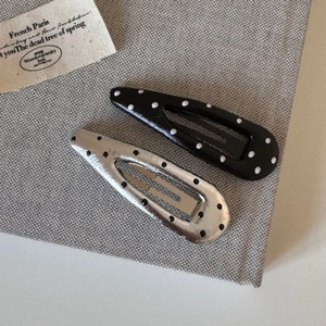 Close-up of elegant polka dot hair clips with silver and black glossy lacquer finish