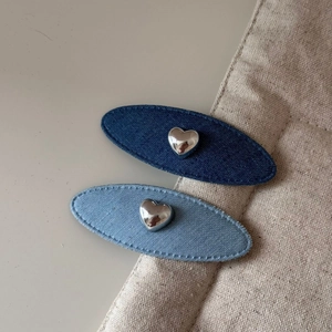 Détail de barrettes ovales en denim bleu avec des accents de cœur en métal argenté