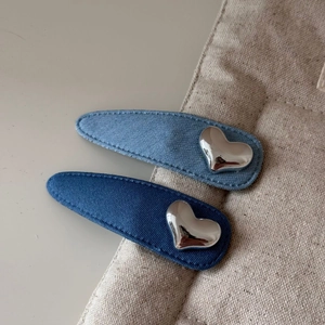 Gros plan de barrettes ovales en denim avec détail de coeur argenté en bleu clair et foncé
