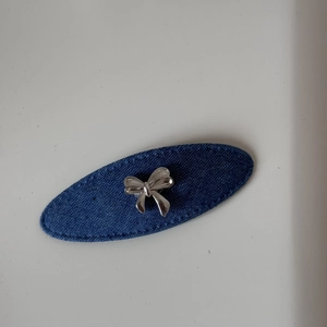Vue macro d'une pince à cheveux ovale en denim bleu avec un nœud en forme de cœur argenté
