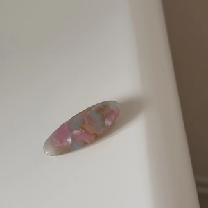 Detail of oval macaron acetate hair clip with marble texture and gold lettering