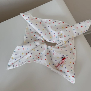 Détail d'un chouchou en tissu blanc avec des pois multicolores et étiquette de marque