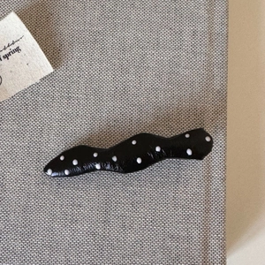 Detail of wavy black hair clip with white polka dots and glossy resin finish