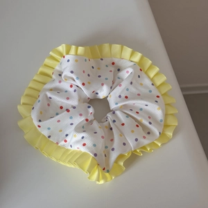 Vue détaillée du chouchou à pois colorés avec bordure en ruban plissé jaune vif