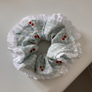 Detail of blue cherry pattern scrunchie featuring layered white lace ruffled edges
