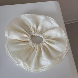 Gros plan sur un chouchou en mousseline double couche avec volants en satin crème et texture