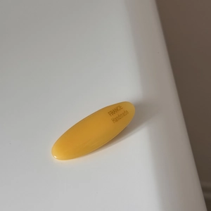 Close-up of yellow oval acetate hair clip with France Handmade engraving detail