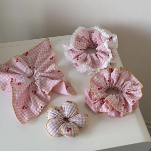 Détail de chouchous à carreaux roses avec motifs cerises et bordure dentelle jaune